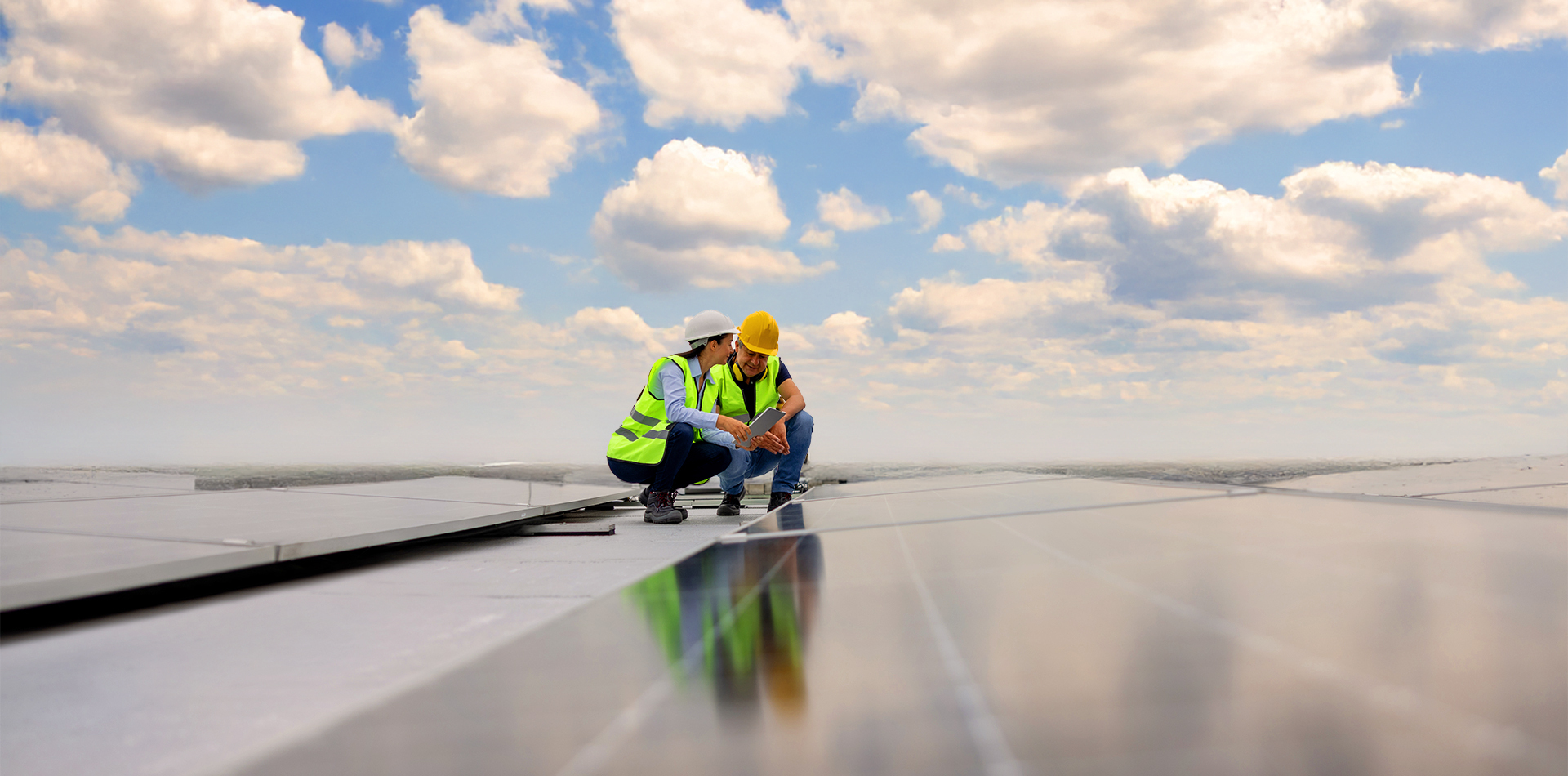 Two workers in hard hats observing a solar panel field.